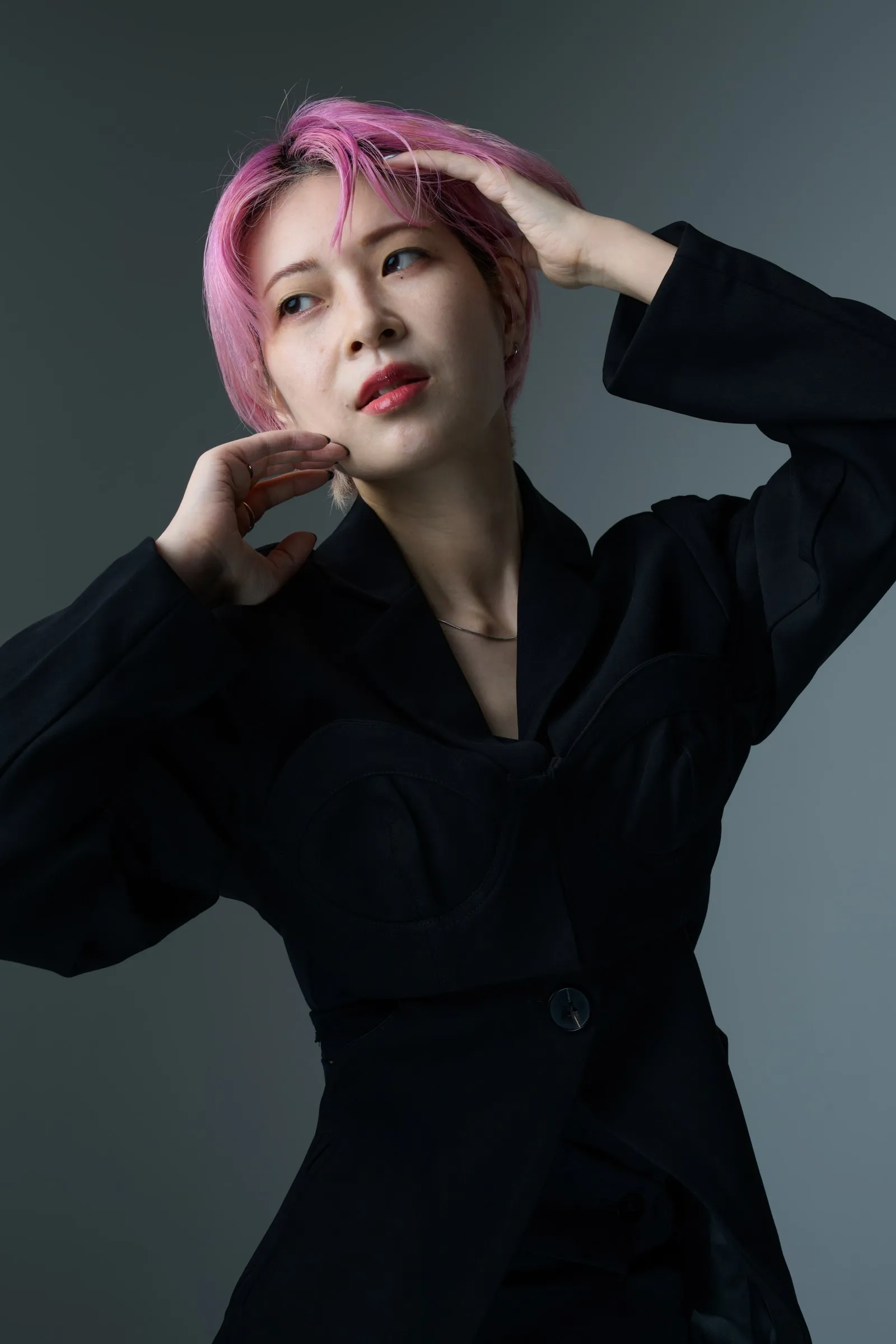 黒い衣装で両手を顔の近くに添えたポートレート