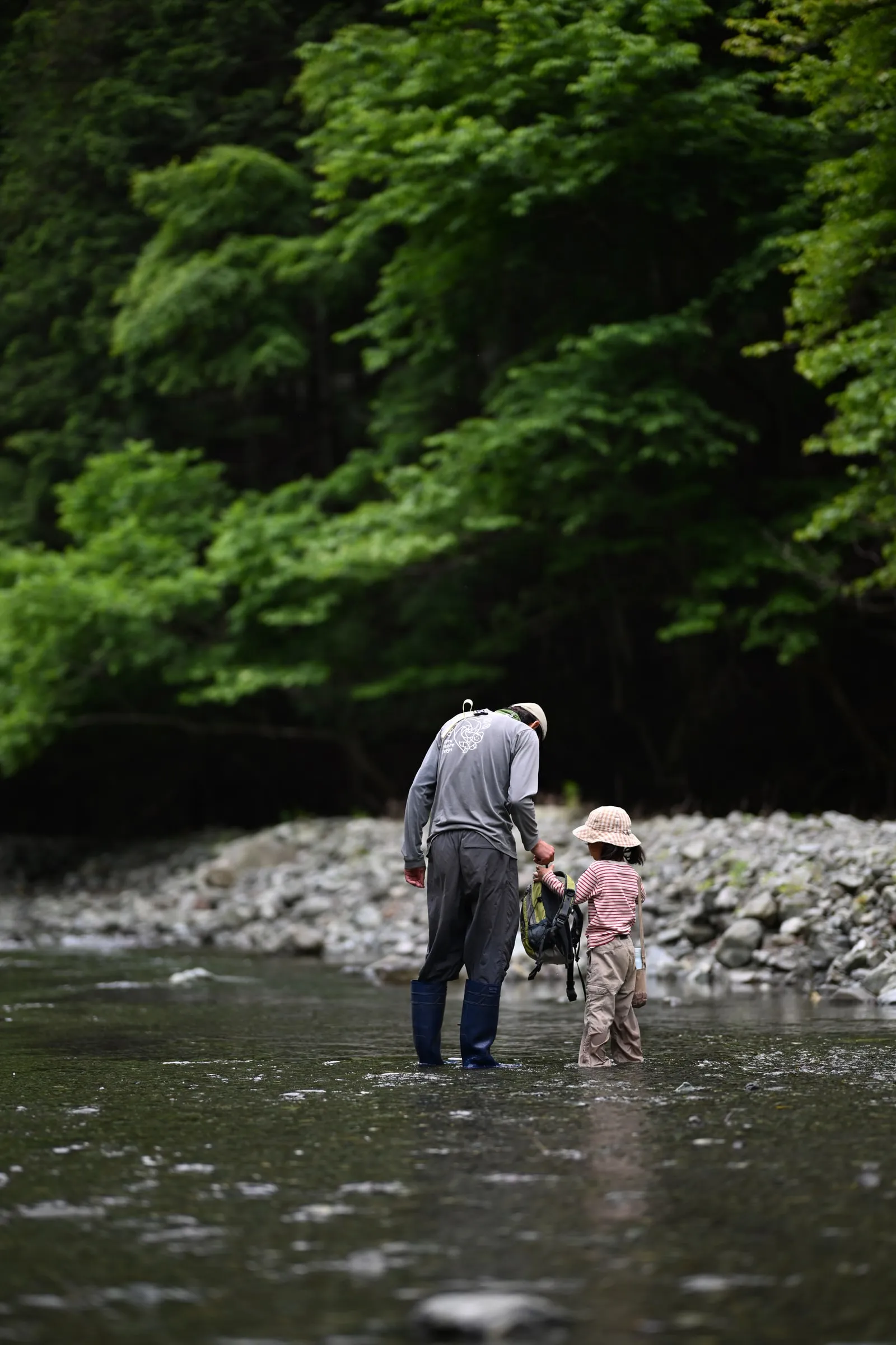 川の中で一緒に歩く大人と子ども