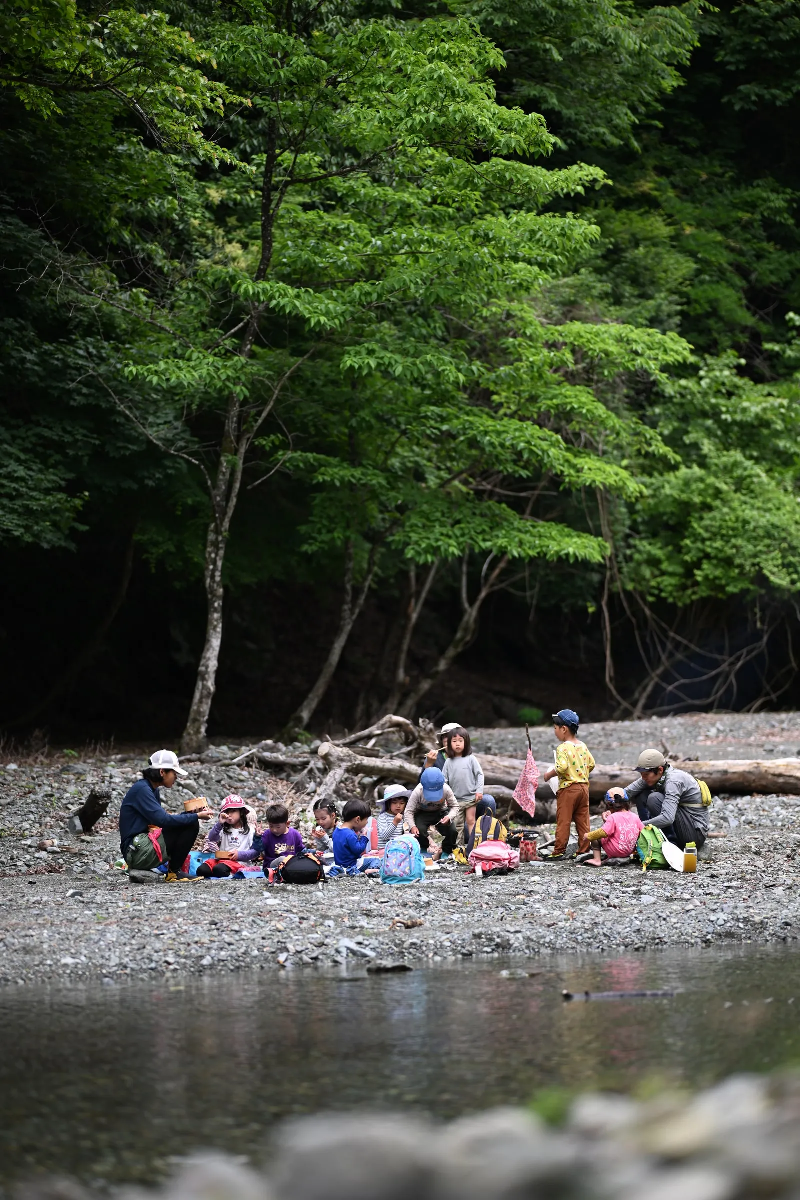 森に囲まれた河原に集まる子どもたち